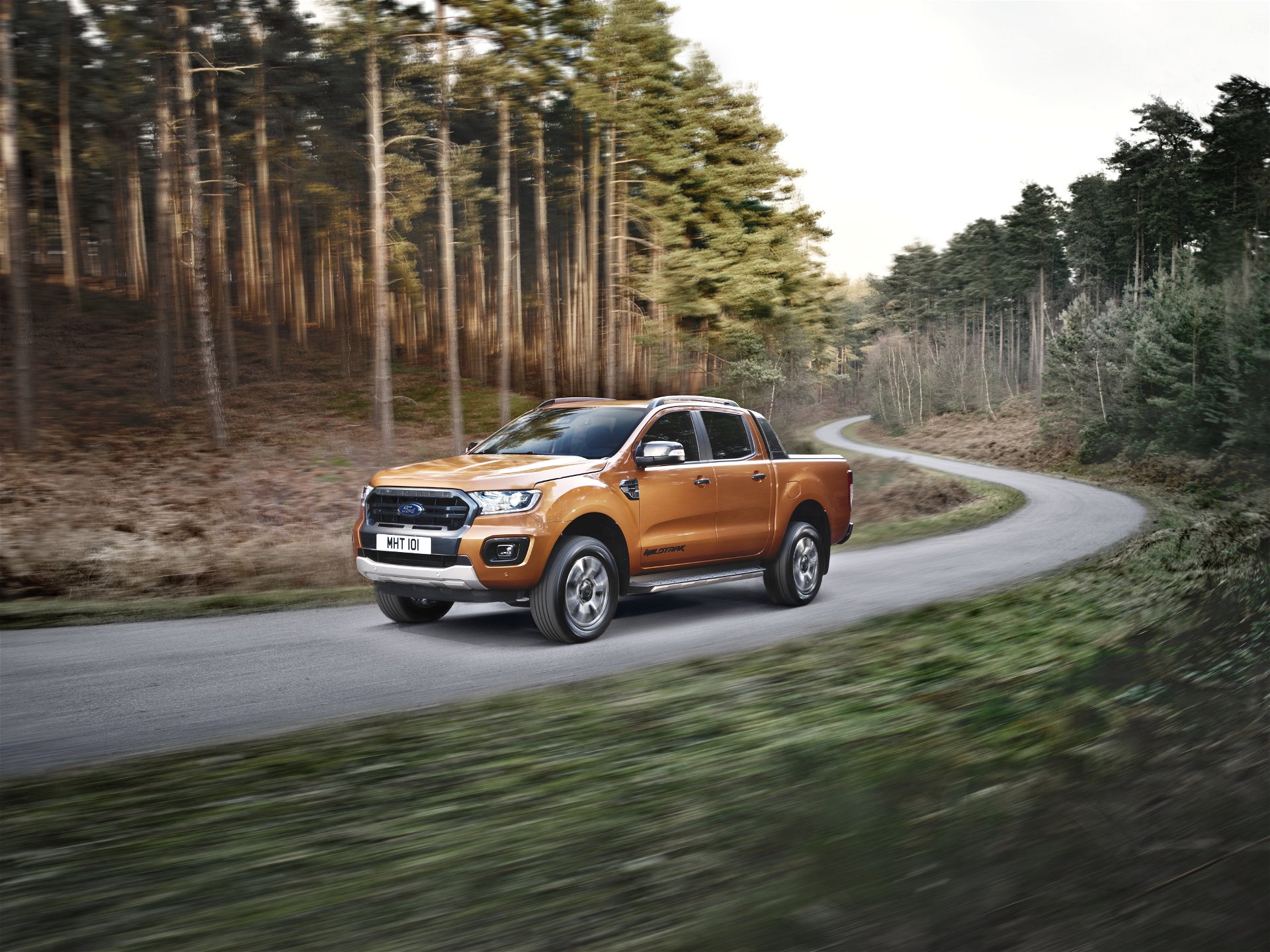 Ford Ranger in orange driving through a forest road