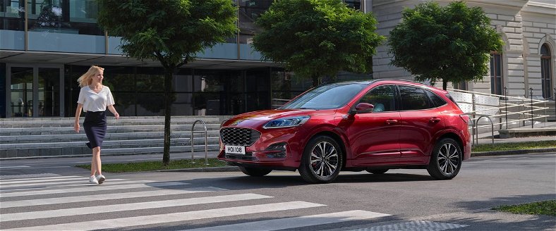 Red Ford Kuga at a pedestrian crossing with a woman crossing infront of the car